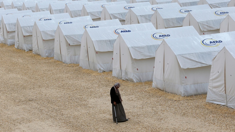 A Kurdish refugee woman from the Syrian town of Kobani walk along tents at a refugee camp in the border town of Suruc